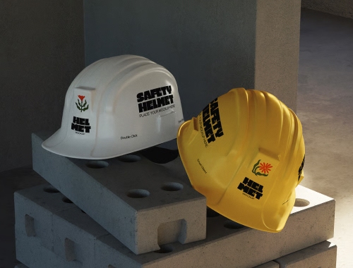 Two construction hard hats, white and yellow, with safety branding, resting on concrete cinder blocks at a work site.